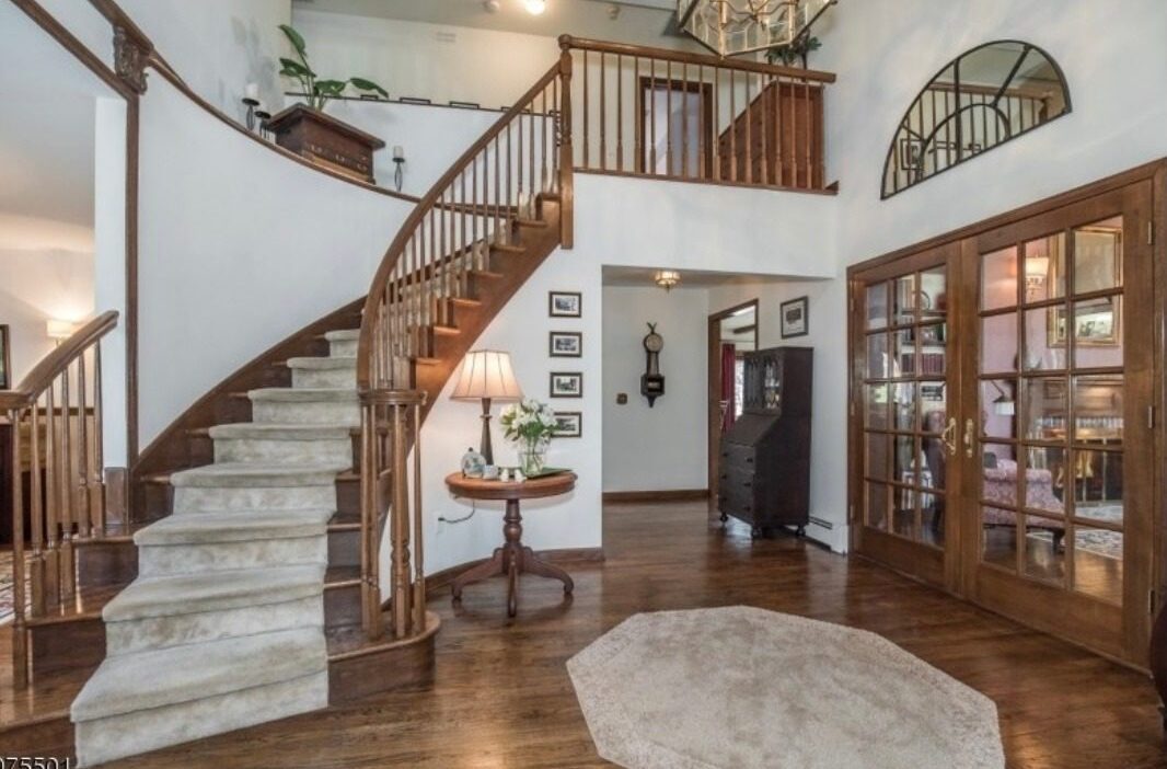 Original foyer of the Tudor home before renovation, showing dated finishes and an unfinished entry layout ready for transformation.
