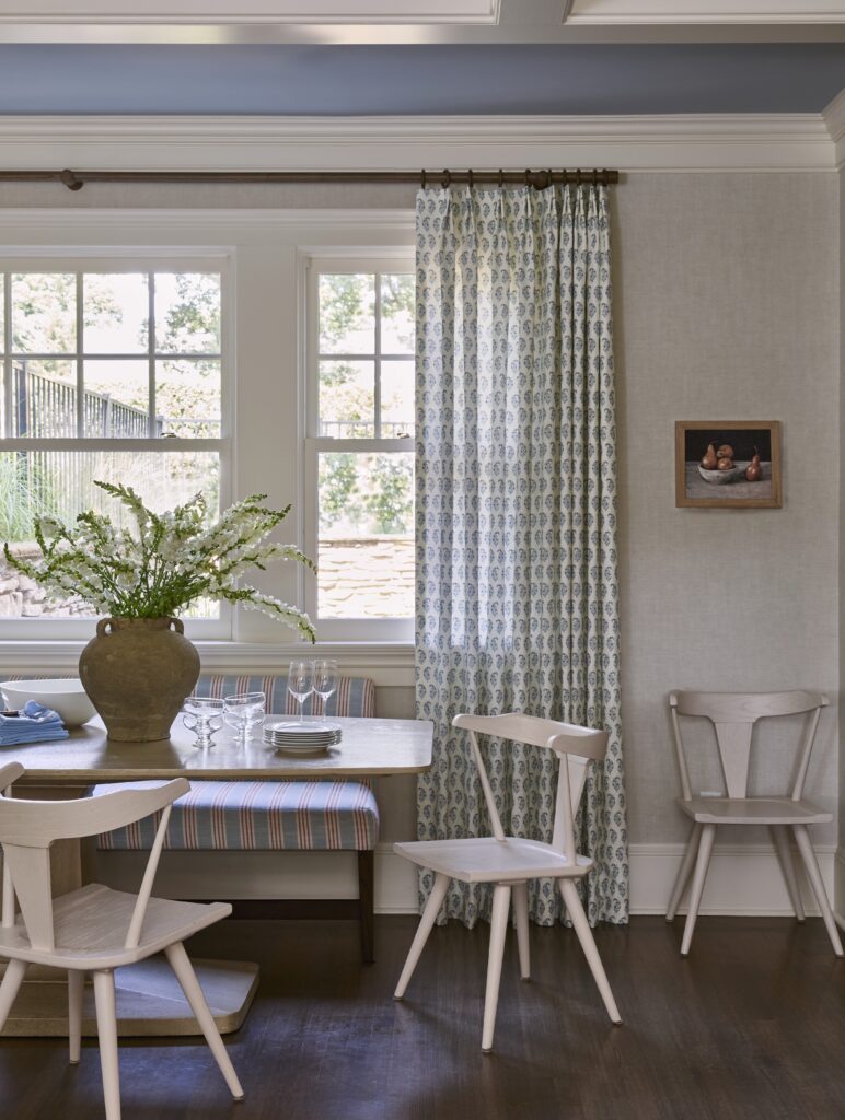 Cozy traditional home breakfast nook off kitchen, red and blue banquette and floral window treatments.